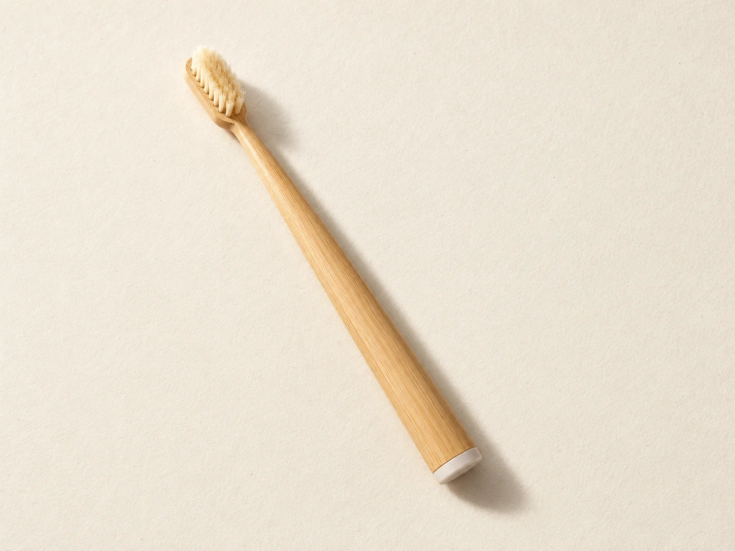 Mumzu bamboo and boar bristle toothbrush on a cream surface